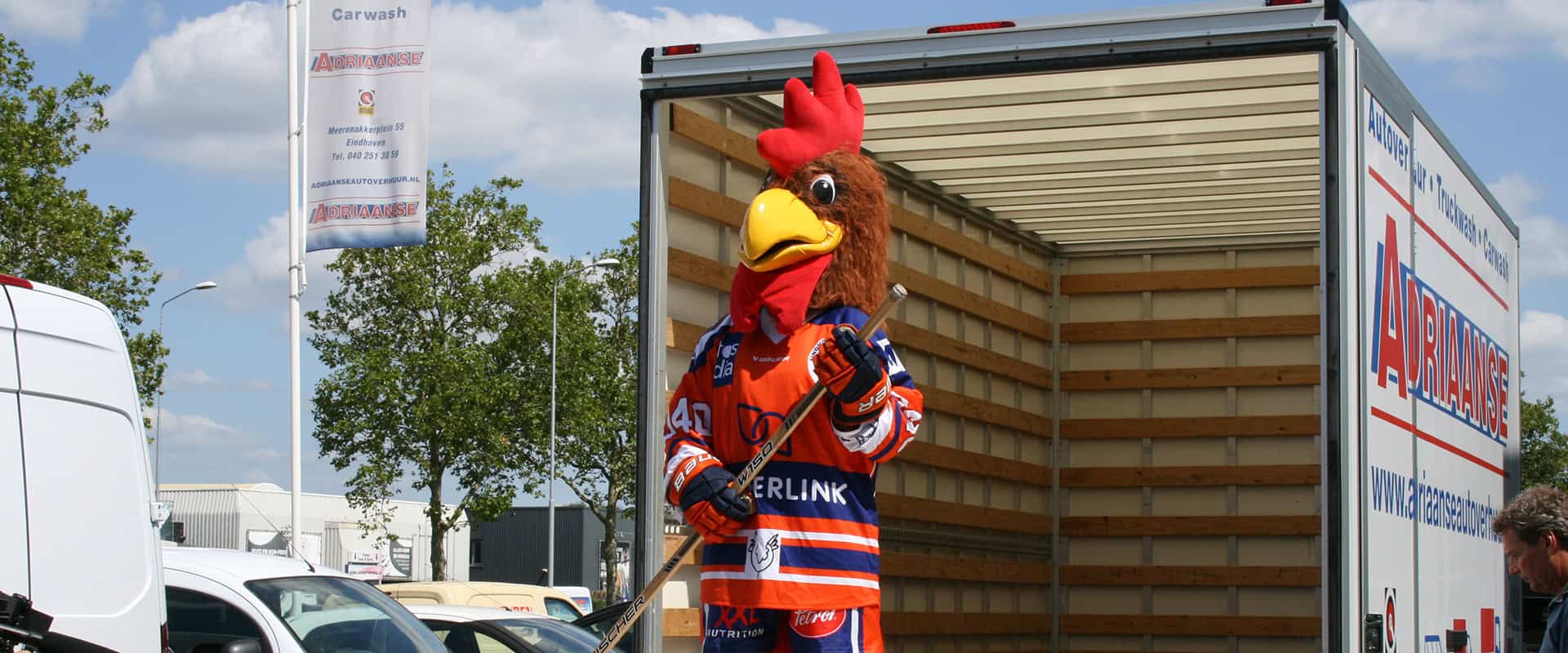 Haanmascotte met hockeystick bij verhuiswagen van Adriaanse